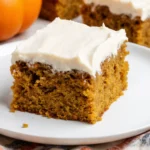 Freshly cooked Pumpkin Bars with Cream Cheese Frosting with golden crispy texture on white plate